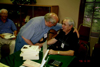 LaVern Freeh autographing his book at the Public Library during the Harvey, North Dakota Centennial, June 30, 2006. He is shaking hands with Dick Biever, teammate in high school track at Harvey.