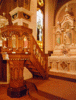 The hand-carved pulpit of Sts. Peter and Paul Church features statuary depicting Christ and the four gospel writers--Matthew, Mark, Luke and John. In the background, right, stands one of the church's ornately carved altars, bedecked with statuary and intricate painting.